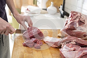 Real men cutting fresh raw meat on board in white kitchen. Preparing pork meat, cooking