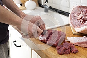 Real men cutting fresh raw meat on board in white kitchen. Preparing pork meat, cooking