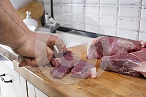 Real men cutting fresh raw meat on board in white kitchen. Preparing pork meat, cooking