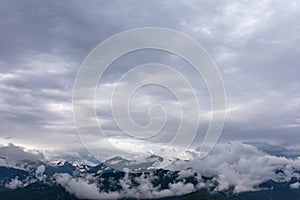 Real mountain landscape. Low clouds over mountains with snowy peaks. Twilight. High point of view