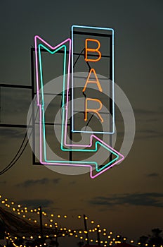 Real neon bar sign and arrow during dawn in a summer festival