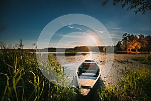 Real Night Sky Stars And Moonrise Above Old Pier With Moored Wooden Fishing Boat. Natural Starry Sky And Countryside