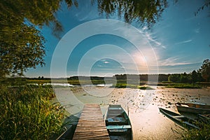 Real Night Sky Stars And Moonrise Above Old Pier With Moored Wooden Fishing Boat. Natural Starry Sky And Countryside