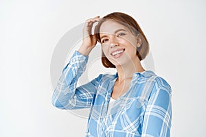 Real people. Beautiful caucasian woman smiling with white teeth, touching hair and looking happy. Young girl with pretty