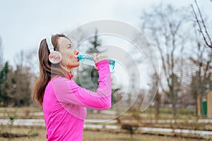 A real people jogger, a woman in her 30s, running and drinking water