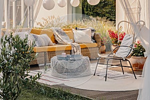 Real photo of an armchair, pouf as a table and couch on a terrace