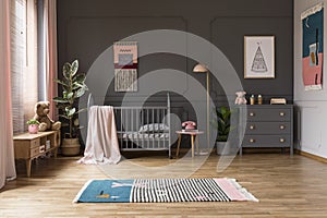 Real photo of a baby crib in a grey child`s room interior, next