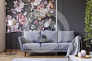 Real photo of dark living room interior with glass lamp, floral