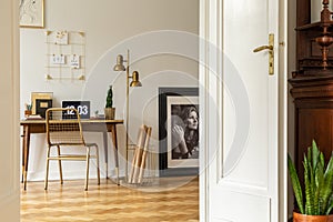 Real photo of an elegant home office interior with golden accents. View through opened door