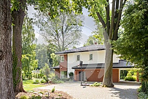 Real photo of an entrance to a house with a basketball playground, trees and bushes