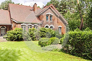 Real photo of garden with bushes and beautiful brick house