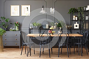 Real photo of a gray and black dining room interior with posters