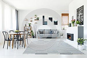 Real photo of a grey sofa standing in spacious living room with