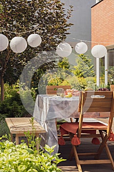 Real photo of lamps in a garden above a table and chairs