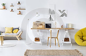 Modern home office interior with graphics, desk, sofa and yellow pouf photo