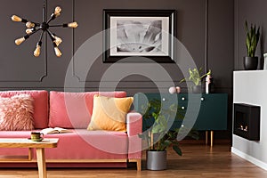 Real photo of powder pink sofa with open book standing in dark l