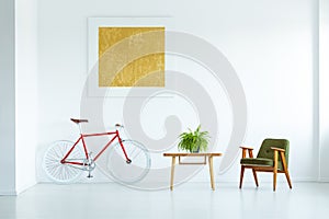 Real photo of a table with a plant standing between an armchair