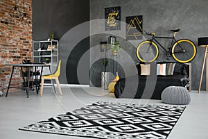 Real photo of a teenager`s bedroom interior with black bed, bike