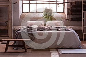 Wabi sabi bedroom interior with a bed, plant and wooden stool in front photo