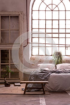 Wabi sabi bedroom interior with a big, old window and bed photo