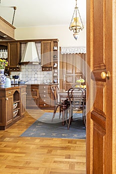 Real photo of a wooden kitchen interior with cupboards, dining t