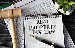REAL PROPERTY TAX LAW - words on a white sheet on the background of a judge\'s gavel, a cactus and a pen