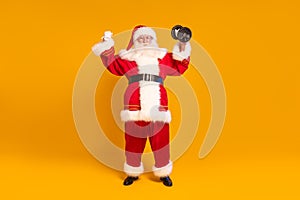 Real Santa Claus doing fit gym exercise. Christmas time. Xmas vibes. A lot of copy space on the yellow studio background
