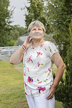 Real Smiling Retired 70 yo Woman Looks Away. Green Trees and Sky on Background. Portrait