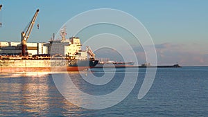 Real time shot of large freighters docked at the port on sunny day.