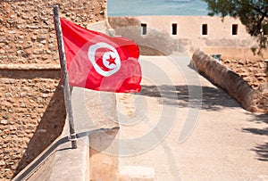 Real Tunisia flag against of the medina`s old fortress wall