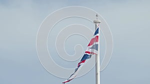 Real Union Jack flag of the United Kingdom on flagpole fluttering in the wind