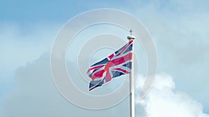 Real Union Jack flag of the United Kingdom on flagpole fluttering in the wind