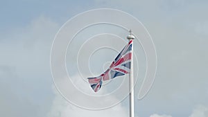 Real Union Jack flag of the United Kingdom on flagpole fluttering in the wind