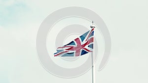 Real Union Jack flag of the United Kingdom on flagpole fluttering in the wind