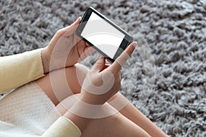 Real woman with a mobile phone in her hands sitting in her living room. space for mock up, application or news portal on the