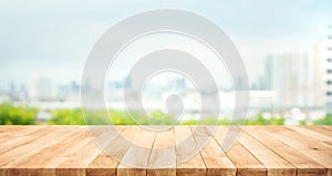 Real wood table top texture on blur leaf tree garden and wall building from city,park background