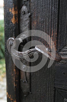 Real wooden door with a hand-wrought iron handle. Wood with iron for background. A wooden texture with an iron lock of old times.