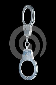 real zinc plated steel police handcuffs closed hanging vertically, isolated on black background