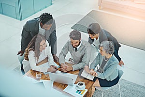 Realising their business vision together. High angle shot of a group of businesspeople having a meeting in an office.