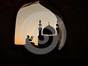 A realistic Arabian interior miniature with window and columns. Silhouette of muslim praying on carpet near window. Festive