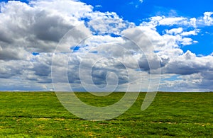 Realistic blue cloudy sky with bright sun over green meadow field