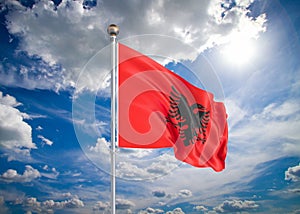 Realistic flag. 3D illustration. Colored waving flag of Albania on sunny blue sky background