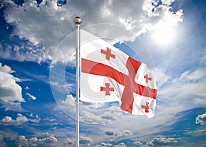 Realistic flag. 3D illustration. Colored waving flag of Georgia on sunny blue sky background