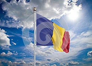 Realistic flag. 3D illustration. Colored waving flag of Romania on sunny blue sky background