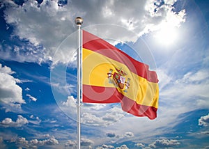 Realistic flag. 3D illustration. Colored waving flag of Spain on sunny blue sky background