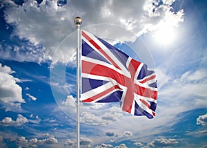 Realistic flag. 3D illustration. Colored waving flag of United Kingdom on sunny blue sky background