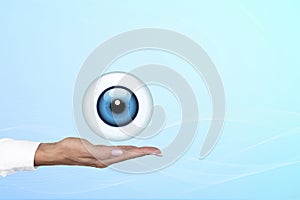 Realistic human eye with blue cornea in the form of a round icon on the palm of a doctor, woman. Gradient blue background. Copy