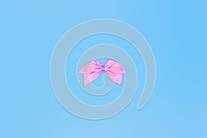 Realistic pink ribbon, bow on a blue background, the concept of a holiday card