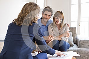 Realtor agent presenting a contract for apartment investment to a cheerful couple