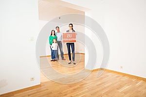 Realtor In Empty Apartment, Holding `zu Verkaufen` Sign photo